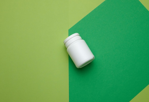 Vaso in plastica bianca per pillole crema e medicinali su sfondo verde Contenitore per sostanze vista dall'alto