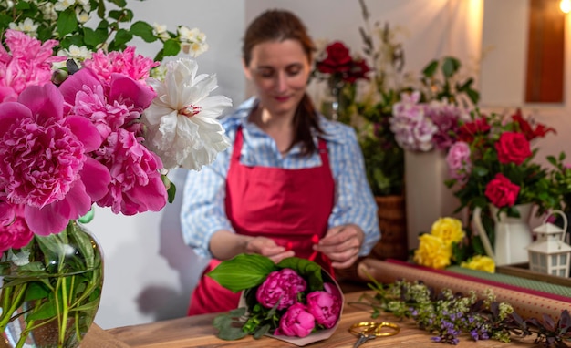 Vaso in vetro con vista ritagliata con peonie in fiore il venditore di fiori Attività floristica