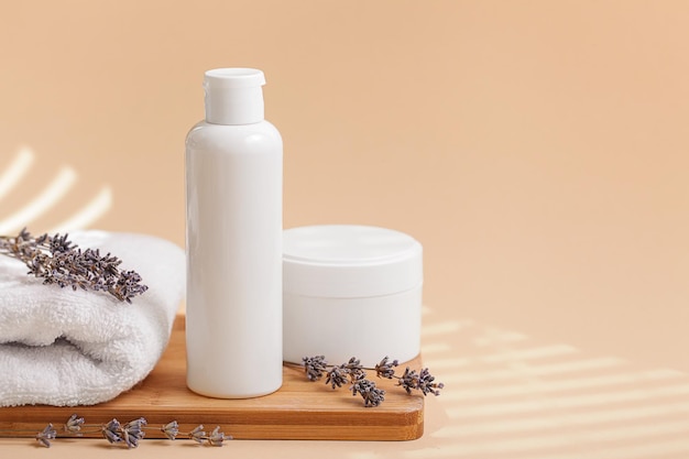 Vaso Spa con telo da bagno crema idratante per il corpo fiore di lavanda su sfondo beige Concetto cosmetico per la cura della pelle Spazio per la copia della composizione in stile minimale