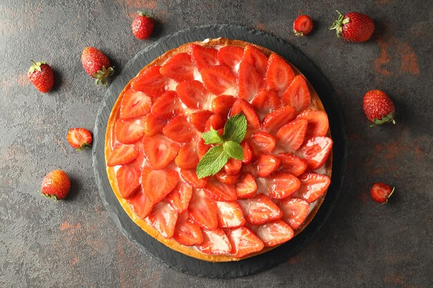 Vassoio con crostata di fragole sul tavolo a trama scura.