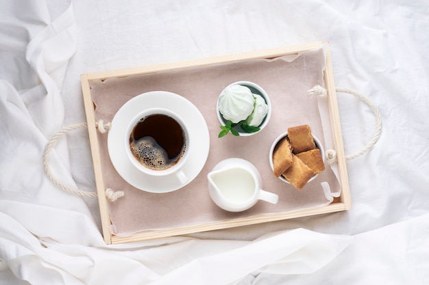 Vassoio della colazione, caffè del mattino con dolci su lenzuola bianche