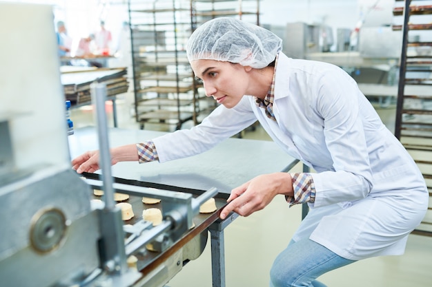 Vassoio della tenuta del confettiere con pasticceria mentre azionando macchina