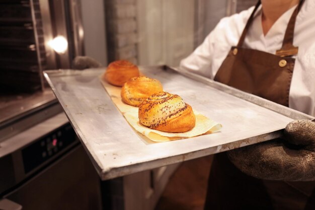 Vassoio della tenuta della donna con i panini in panetteria