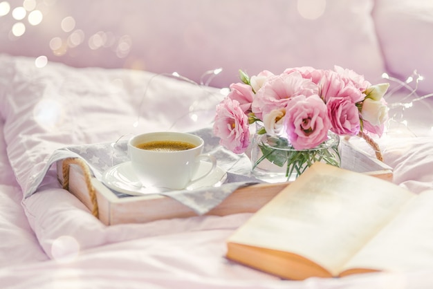 Vassoio in legno con tazza di caffè, libro e fiori di lisianthus rosa