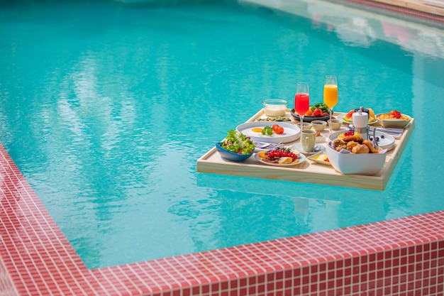 Vassoio per la colazione in piscina, colazione galleggiante in hotel di lusso. Stile di vita da resort sulla spiaggia tropicale