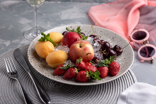 Vassoio sano della frutta, fragole, mele, pesche, albicocche su una tavola di legno grigio scuro, vista superiore, primo piano, fuoco selettivo.