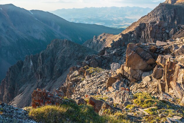 Vastità soleggiata vista sulle montagne dalla scogliera ad altissima quota Paesaggio alpino panoramico con bellissime rocce taglienti e canaloni alla luce del sole Bellissimo scenario montano sul bordo dell'abisso con pietre taglienti