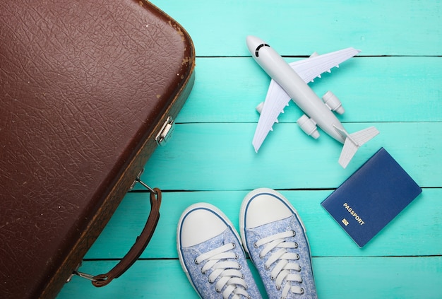 Vecchi bagagli, figurina di aeroplano, passaporto, scarpe da ginnastica sul pavimento di legno blu