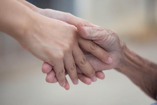 Vecchi e giovani che si tengono per mano sul primo piano chiaro del fondo