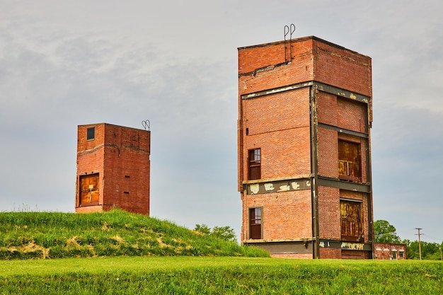 Vecchi edifici in decomposizione su una collina erbosa sotto un cielo grigio che un tempo erano vecchi ascensori merci