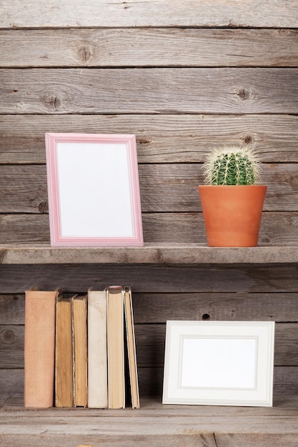 Vecchi libri e cornici per foto su uno scaffale di legno