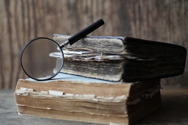 Vecchi libri su un tavolo di legno e lente d'ingrandimento in vetro