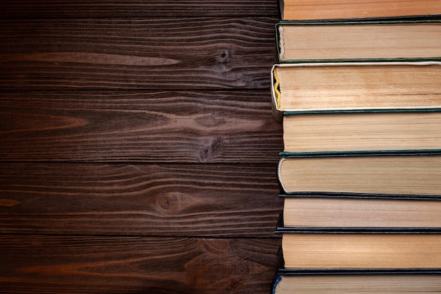 Vecchi libri Un certo numero di vecchi libri chiusi usati con copertina rigida in polvere su sfondo di legno scuro