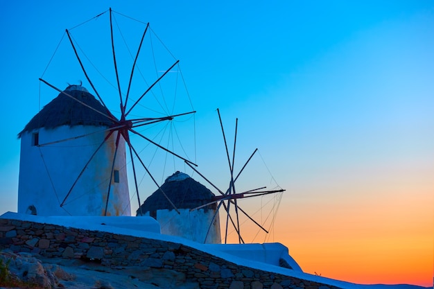 Vecchi mulini a vento nell'isola di Mykonos sulla riva del Mar Egeo al tramonto, Cicladi, Greece