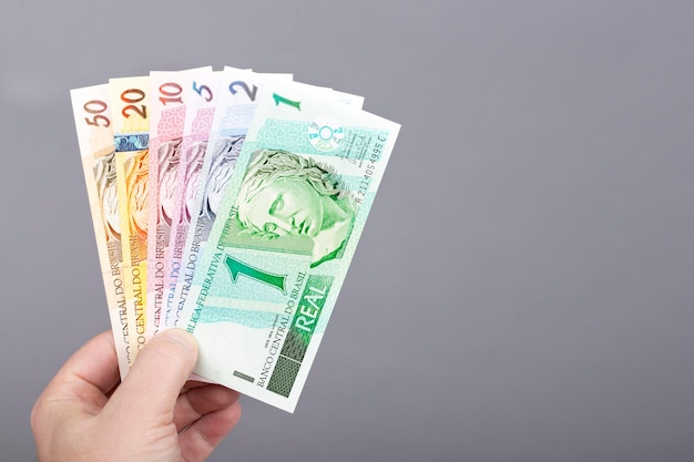 Vecchi soldi brasiliani in mano su uno sfondo grigio