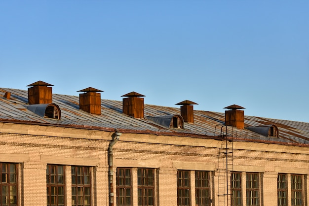 Vecchi tubi di ventilazione arrugginiti sul tetto di un edificio a più piani