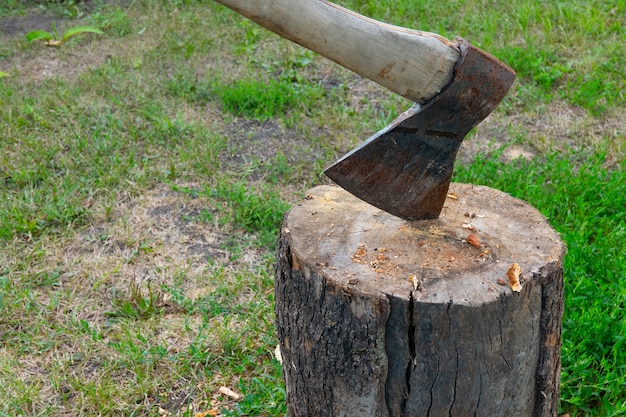 Vecchia ascia vintage incastrata nel ceppo di legno usata per tagliare altri ceppi di legno