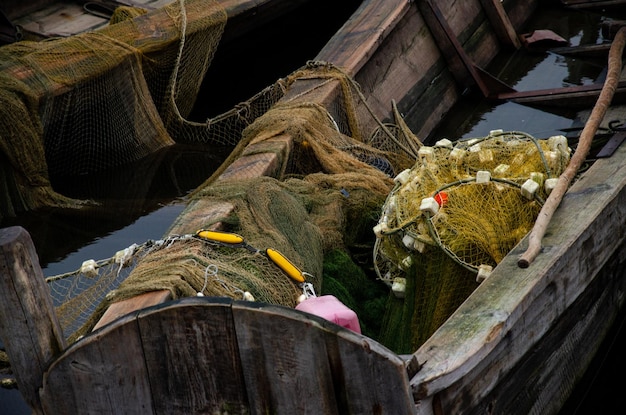 Vecchia barca da pescatore in legno con una pagaia All'interno c'è una rete da pesca e altri attrezzi da pesca Un buon modo per fare soldi per gli abitanti del villaggio La barca si riempie d'acqua