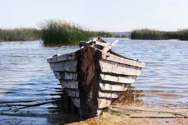 Vecchia barca in legno vicino al lago, usata dalla gente del posto per la pesca, barca in cattive condizioni