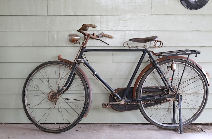 Foto vecchia bicicletta antica sullo sfondo di una parete di legno grigia.