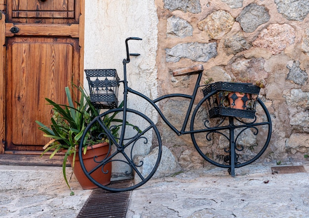 Vecchia bicicletta nera davanti a un muro di pietra e una porta marrone in una città medievale