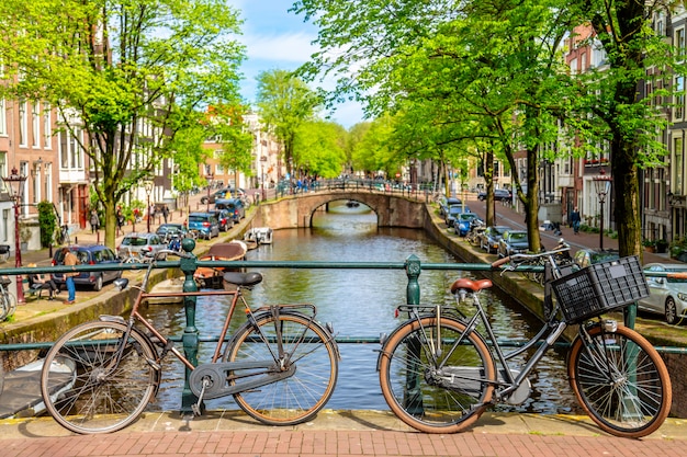 Vecchia bicicletta sul ponte a Amsterdam, Paesi Bassi contro un canale durante il giorno soleggiato di estate.