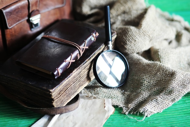 Vecchia borsa in pelle con una lente di ingrandimento su uno sfondo di tavolo in legno marrone viaggiatore con spazio per le copie.