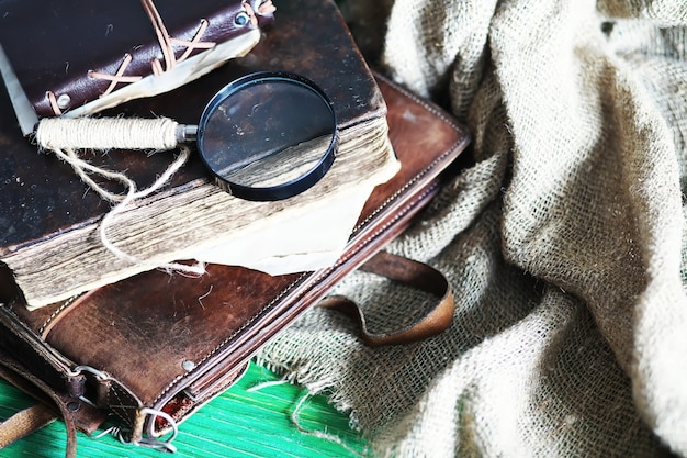 Vecchia borsa in pelle con una lente di ingrandimento su uno sfondo di tavolo in legno marrone viaggiatore con spazio per le copie.