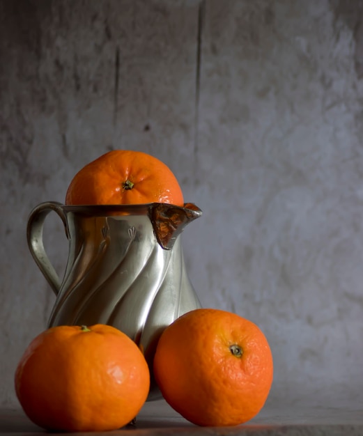 Vecchia brocca di metallo con mandarini