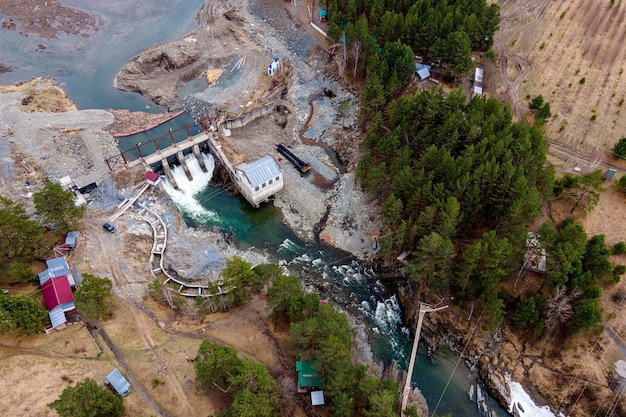 Vecchia centrale idroelettrica sul fiume Chemal ad Altai in una giornata estiva vista aerea dall'alto da droni