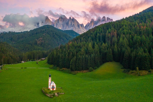 Vecchia chiesa di St Johann nella valle contro le cime dolomitiche al tramonto rosa