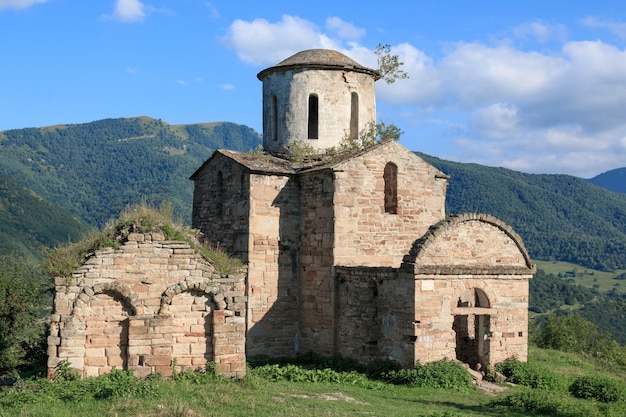 Vecchia chiesa in montagna, nel parco nazionale Dombai, Caucaso, Russia. Paesaggio estivo, tempo soleggiato, cielo azzurro drammatico e giornata di sole