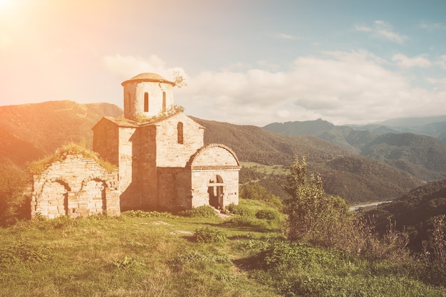 Vecchia chiesa in montagna, nel parco nazionale Dombai, Caucaso, Russia. Paesaggio estivo, tempo soleggiato, cielo azzurro drammatico e giornata di sole