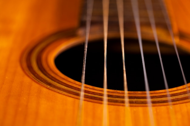 Vecchia chitarra acustica su una parete nera.