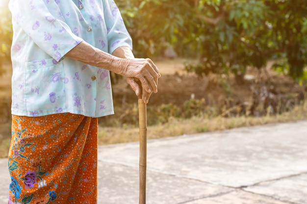 Vecchia donna asiatica in piedi con in mano un bastone di canna di bambù per aiutare a camminare