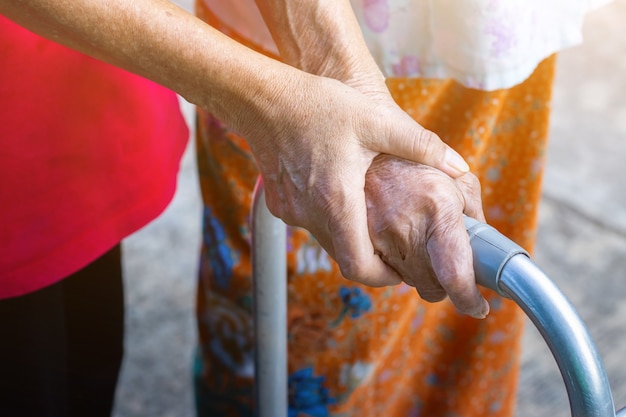 Vecchia donna asiatica in piedi con la sua mano su un deambulatore con la mano della figlia