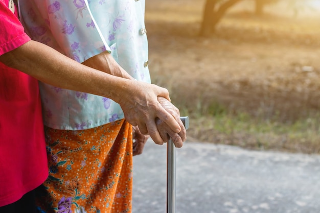 Vecchia donna asiatica in piedi con la sua mano su un deambulatore con la mano della figlia