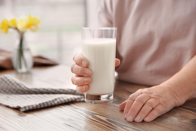 Vecchia donna con un bicchiere di latte fresco sul tavolo