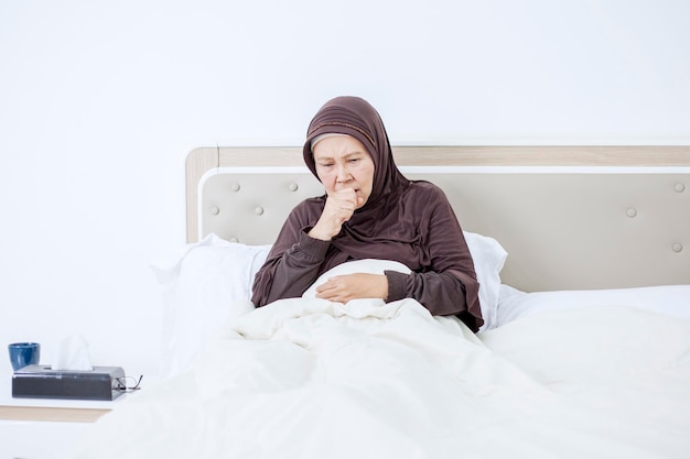 Vecchia donna musulmana che tossisce in camera da letto