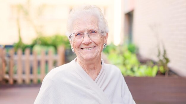 Vecchia donna tenera che sorride alla telecamera fuori da una casa di riposo