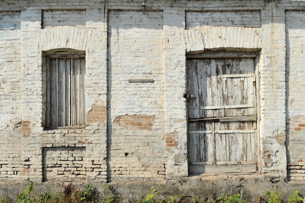 Vecchia facciata in mattoni d'epoca della casa con porta in legno e ricoperta di finestre a pannelli