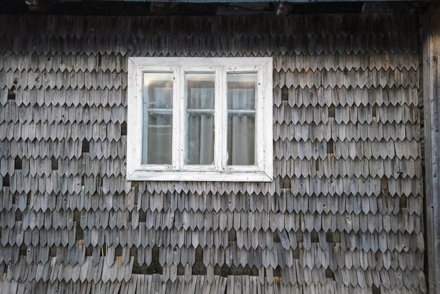 Vecchia finestra bianca sulla parete della casa tradizionale Hutsul con scale di legno