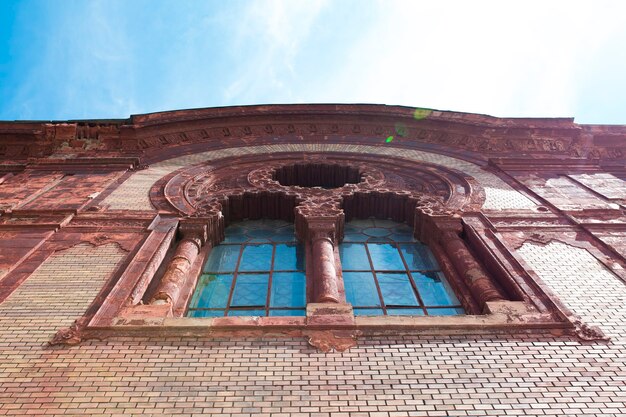 Vecchia finestra della modanatura dello stucco sulla facciata della chiesa con il chiarore del sole in Uzhgorod