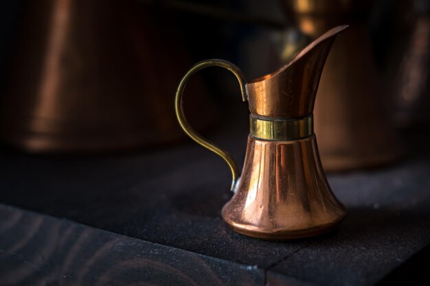 Vecchia lattiera in rame per colazione con caffè con sfondo scuro