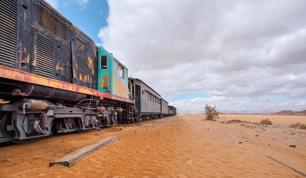 Vecchia locomotiva diesel inutilizzata e treno alla stazione ferroviaria di Wadi Rum deserto sabbioso intorno