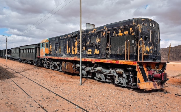 Vecchia locomotiva diesel inutilizzata e treno alla stazione ferroviaria di Wadi Rum deserto sabbioso intorno