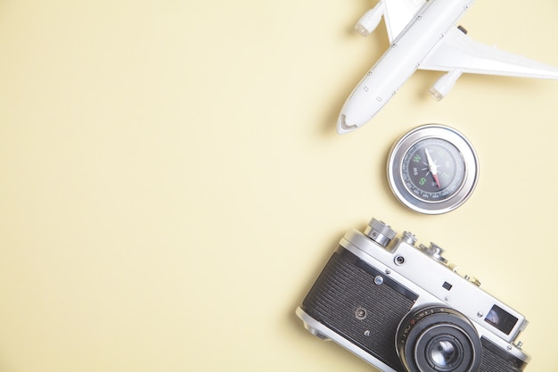 Vecchia macchina fotografica, aeroplano giocattolo e bussola su sfondo giallo.