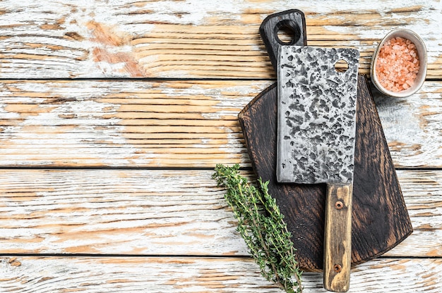 Vecchia mannaia da macellaio di carne. Fondo in legno bianco