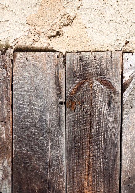 Vecchia parete della pannocchia con superficie incrinata e vecchie schede di legno