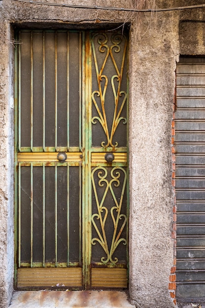 Vecchia porta d'ingresso in legno sulla facciata dell'antico edificio barocco nell'architettura tradizionale di Catania Sicilia, Italia.
